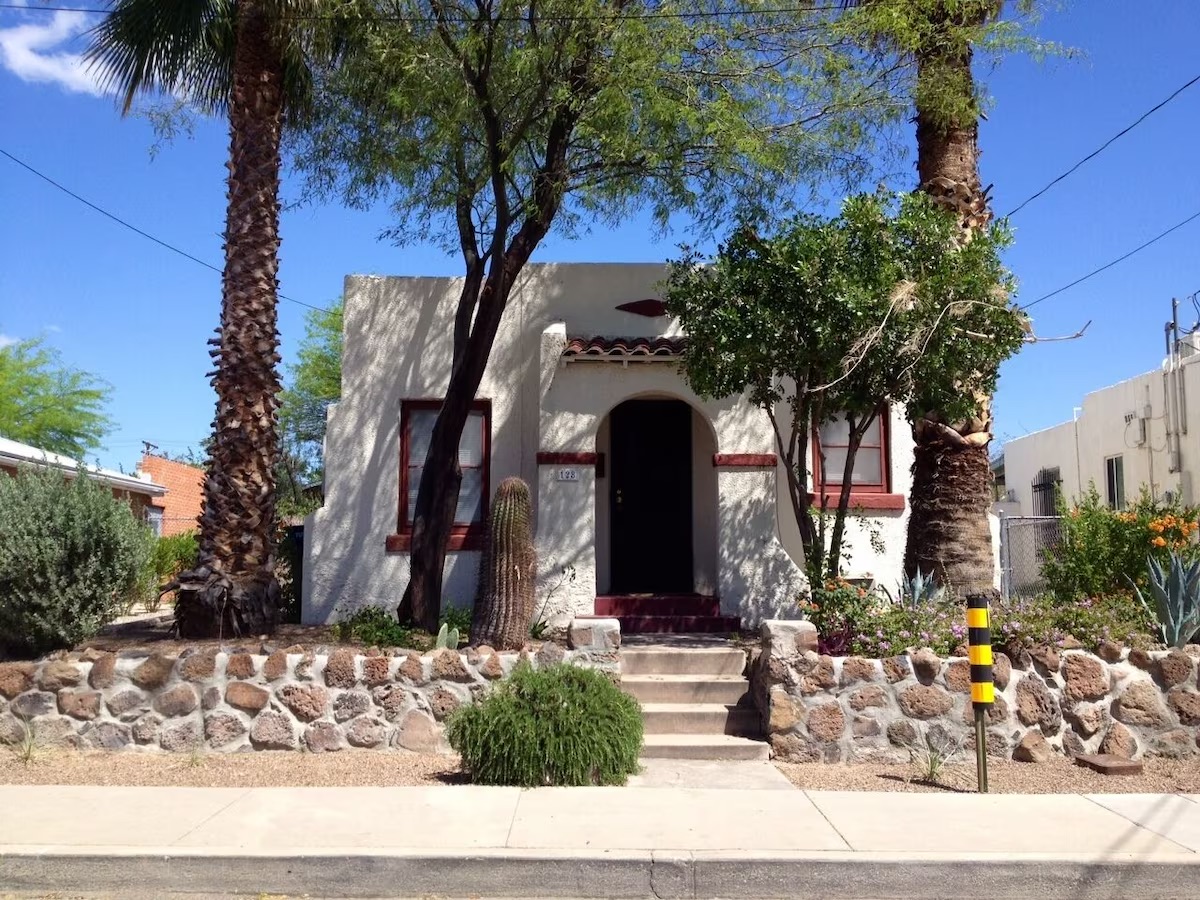 outdoor view of this adorable adobe VRBO home with large palm trees in the front yard 