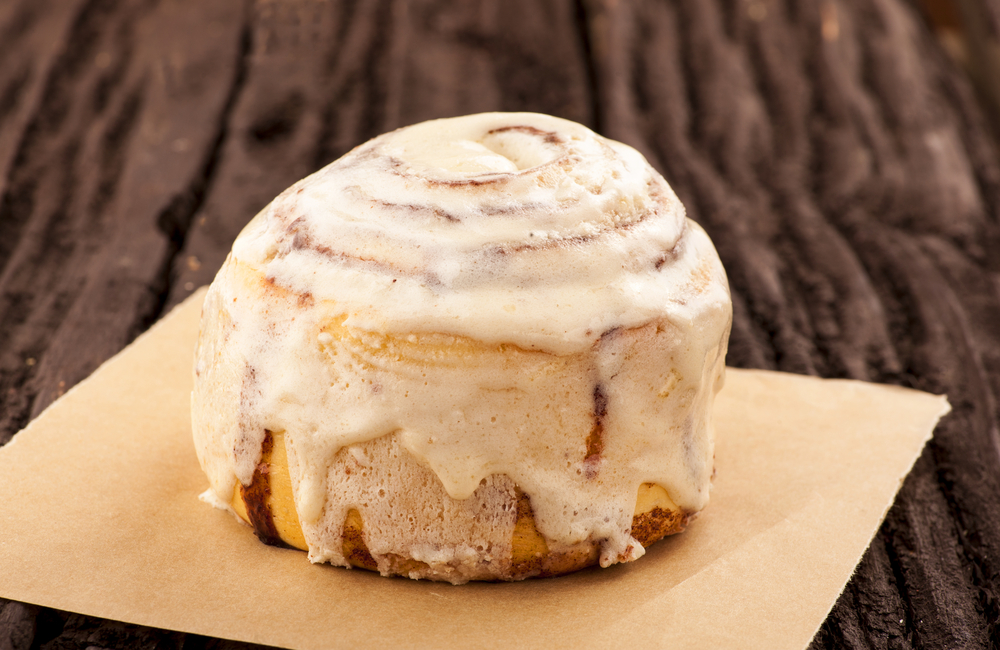 A huge cinnamon roll on a brown paper  towel