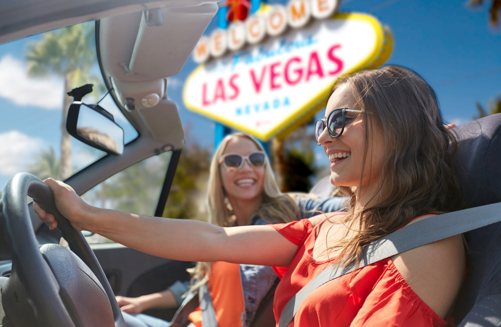 Two women in a car right next to the Las Vegas sign