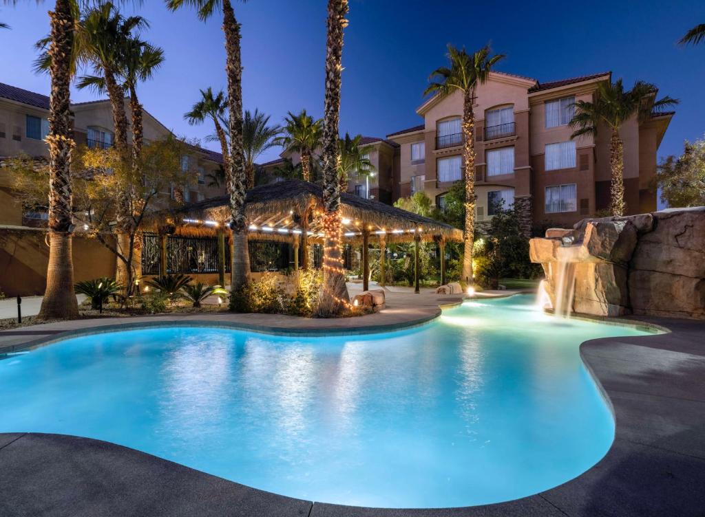 The pool at the Hilton Garden Inn at night with palm trees and a small water feature