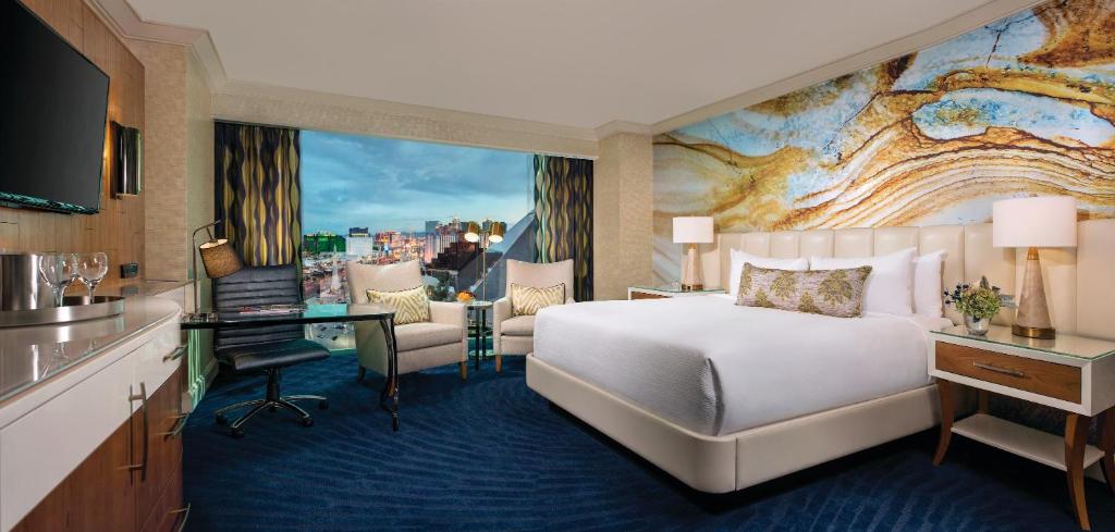 A hotel room with modern decor and floor-to-ceiling windows with a view of Las Vegas