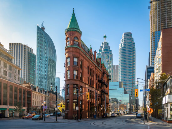 unique building that looks like a flat iron in downtwon Toronto with blue skies