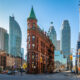 unique building that looks like a flat iron in downtwon Toronto with blue skies