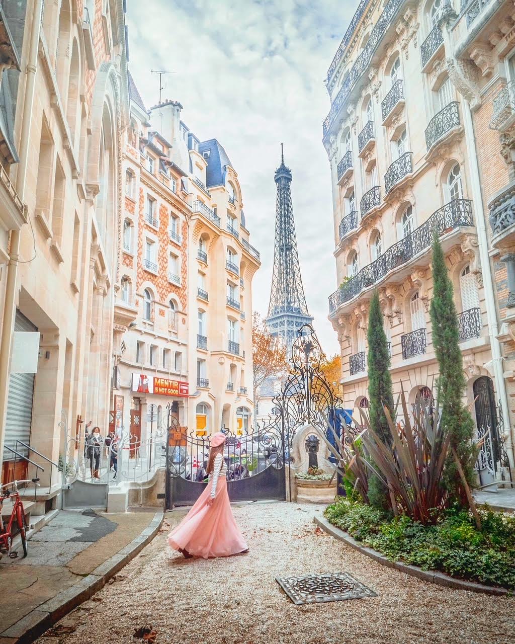 a girl standing in the courtyard overlooking the eiffle tower with buildings surrounding her