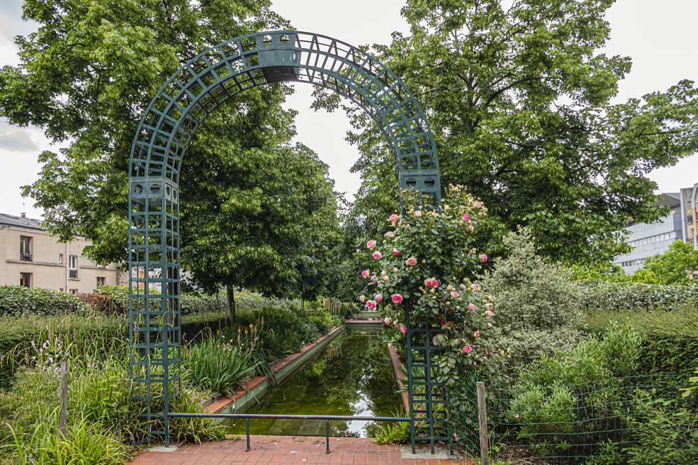 A raised park on an old rail road tracks covered with green trees and water fountains