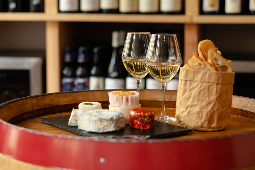two glasses of wine and a plate of cheese in one of the wine bars of Paris perfect for an evening out in Paris during your 4 day trip to Paris