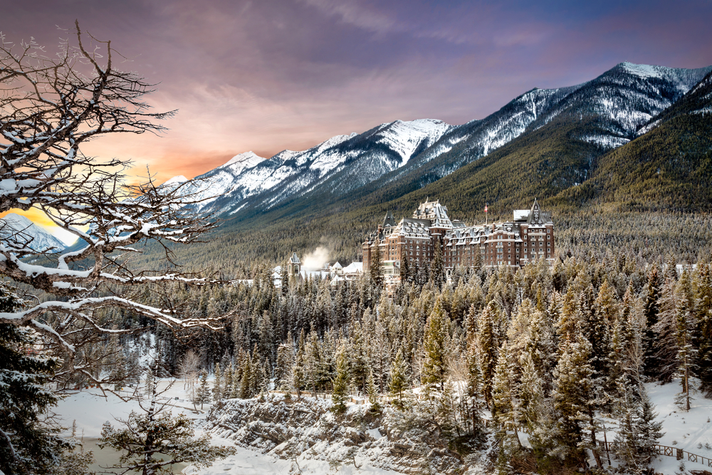 Sunset over Banff Springs Hotel ad mountains on a snowy day.