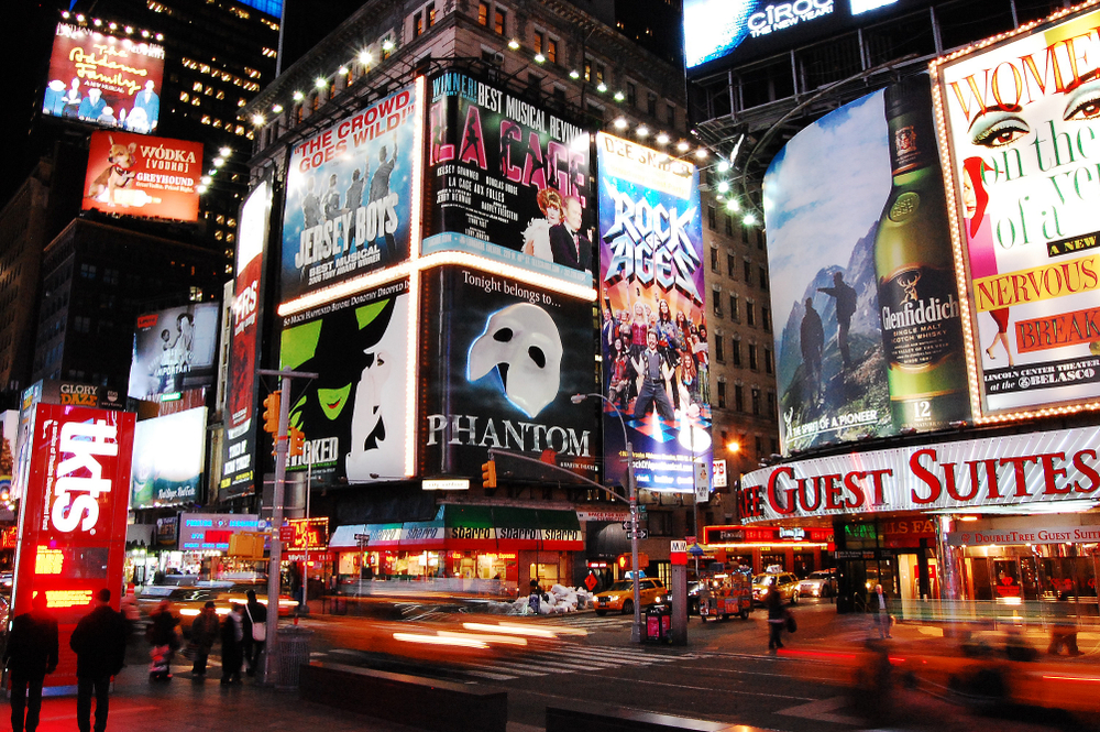 Lit up signs for musicals at night on Broadway in New York in winter.