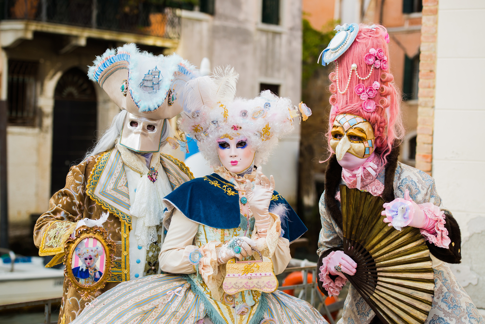 Trio of people dresses in colorful, intricate costumes and masks during Carnival.