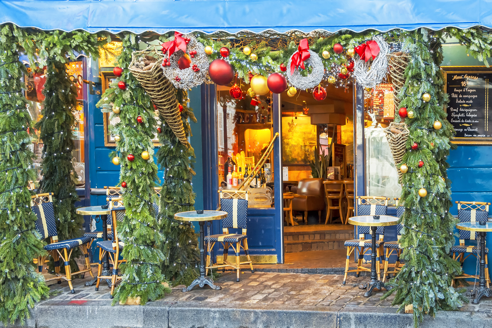 Cute cafe in Paris decorated for Christmas with evergreen branches and ornaments.