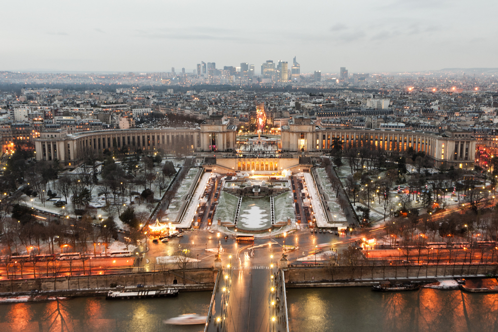 View from the Eiffel Tower of Place du Trocadero and a park dusted in snow on a cloudy day.