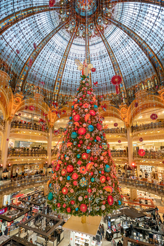Giant hanging Christmas tree with colorful ornaments under a domed, glass ceiling.