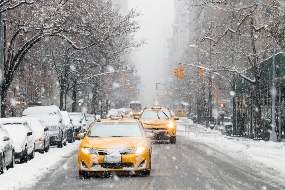 Two yellow taxis driving in a snowstorm in New York City in winter.