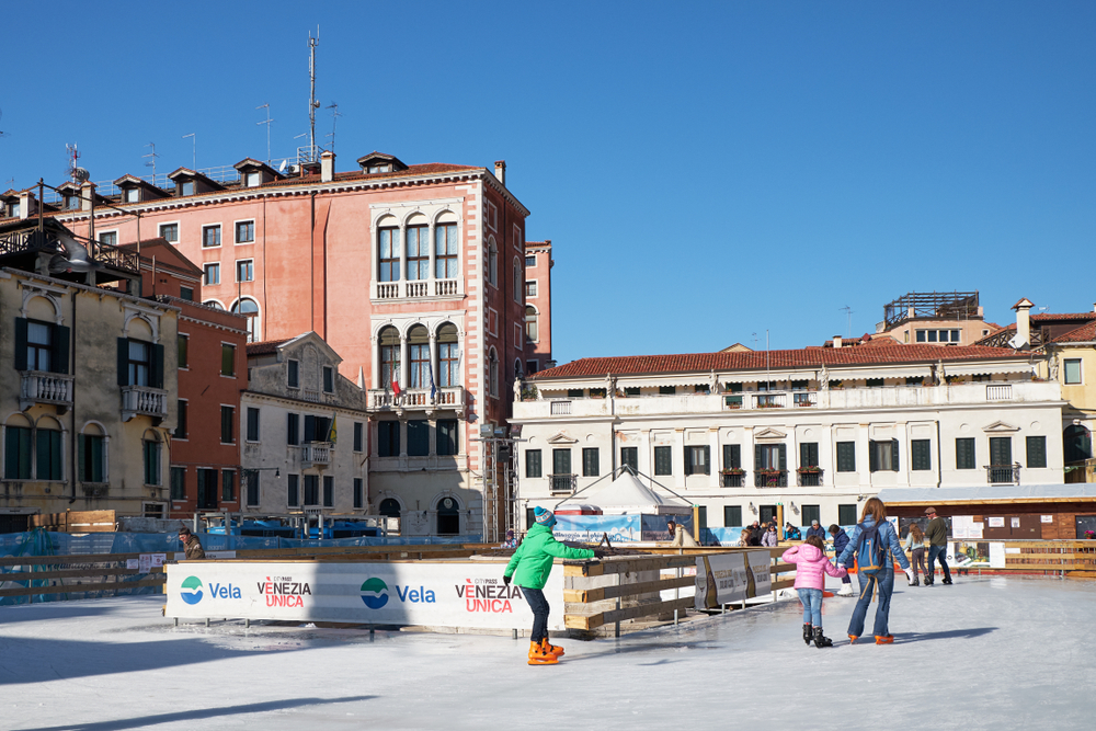 People skating around an ice rink in a Venice square.
