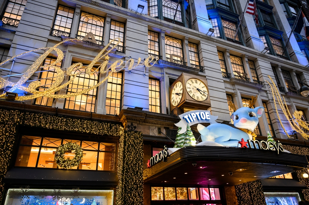 Entrance to Macy's at Herald Square with a big blue reindeer above the door and a lit up sign saying Believe.