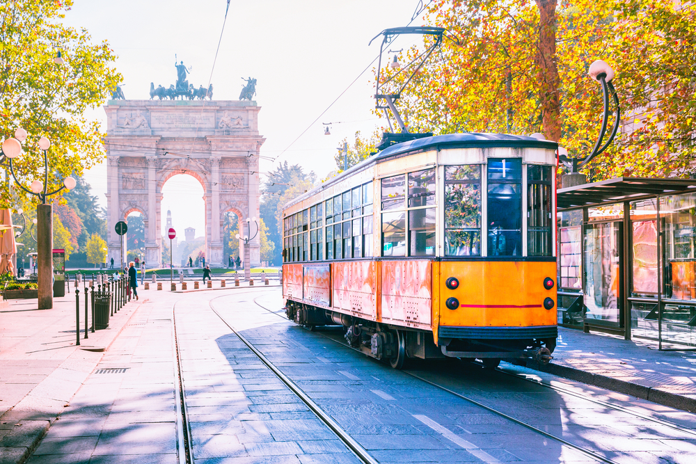 Yellow, historic tram in Milan near an arch during 10 days in Italy itinerary.