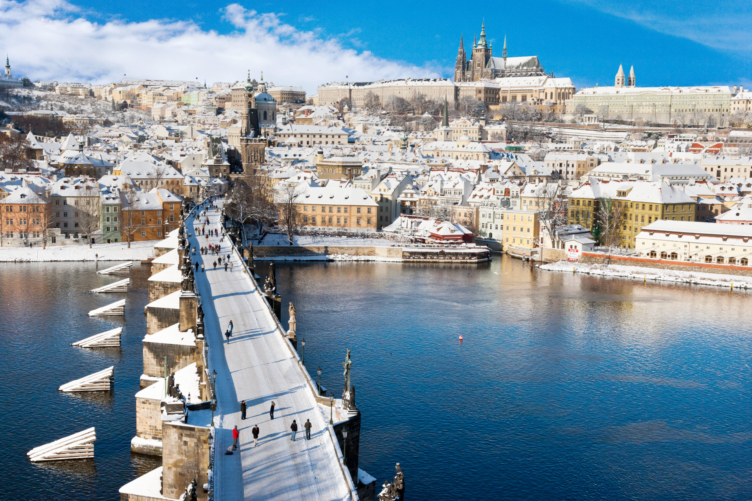 View of a snow dusted downtown Prague and a beautiful pedestrian bridge over the Vltava River 