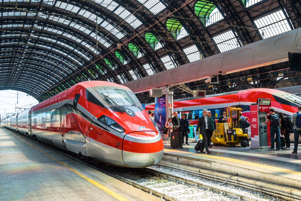 Two red trains at a covered train station in Italy.