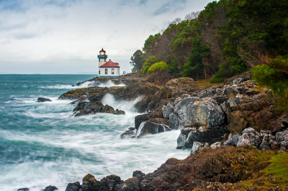 Lime Kiln Lighthouse on a rugged coastline with waves.