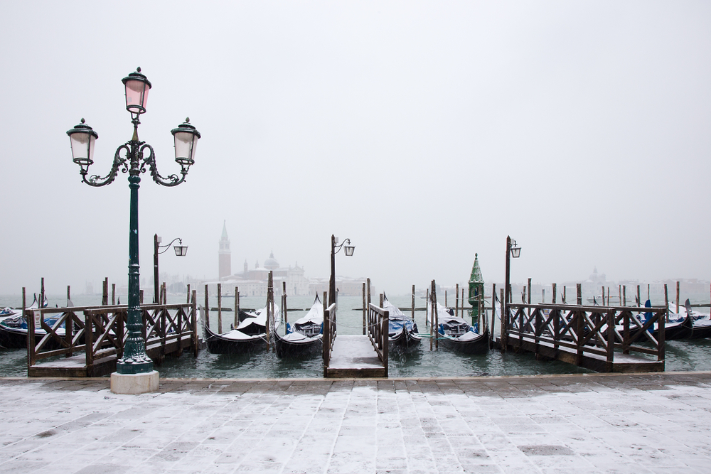 Row of docked gondolas and a lamppost covered in light snow.