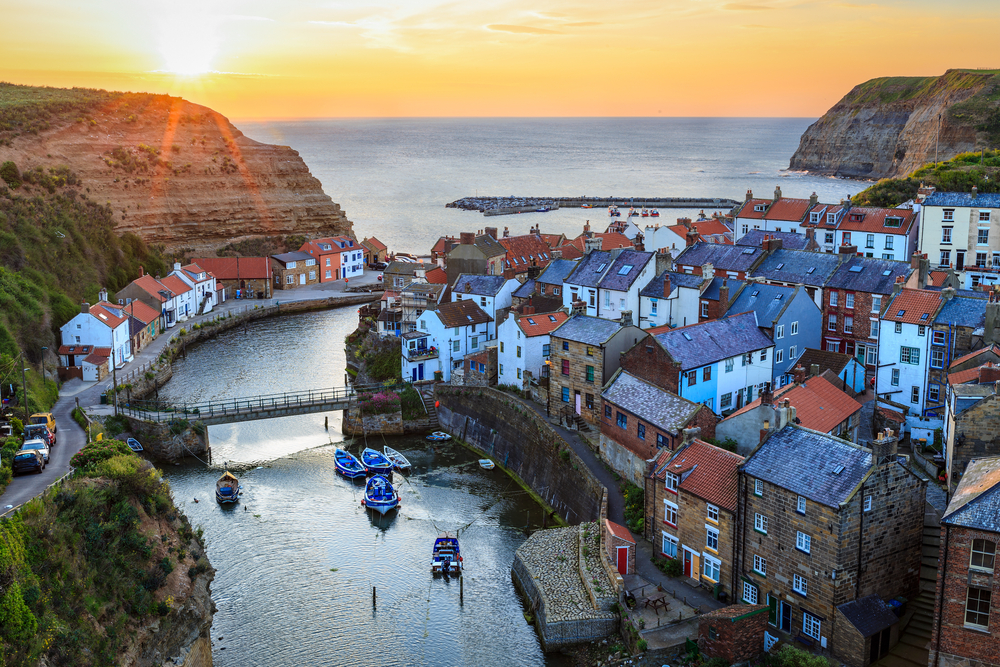 View of Staithes from the top pf a hill you can see the river with boats on the village and the sea on the background