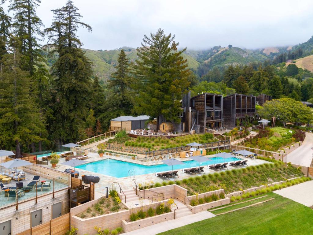 A resort a Big Sur in the mountains featuring buildings and a poll and surrounding landscaped grounds.  