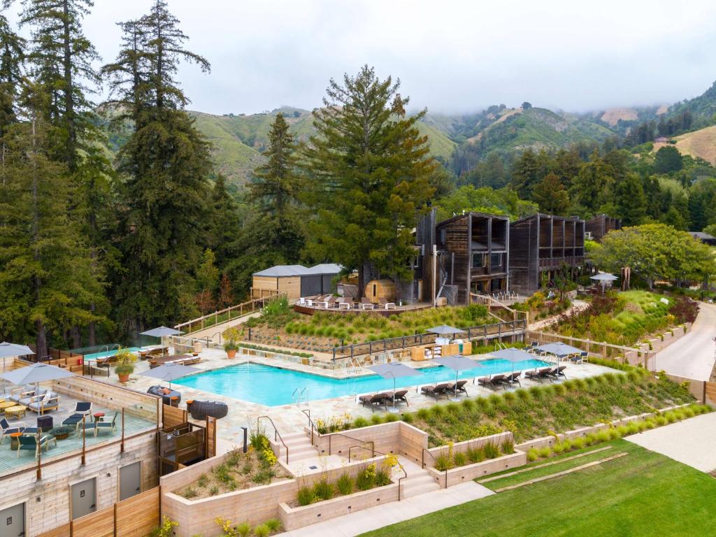 A resort a Big Sur in the mountains featuring buildings and a poll and surrounding landscaped grounds.
