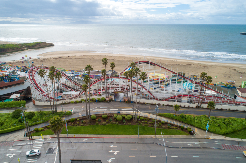 Santa Cruz Beach Boardwalk with a rollercoaster and a beach and the sea in the background. The article is about San Francisco to Los Angeles Road Trip  