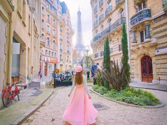 woman standing in a pink skirt and looking at the Eiffel Tower in the background