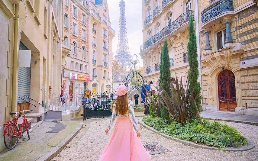 woman standing in a pink skirt and looking at the Eiffel Tower in the background