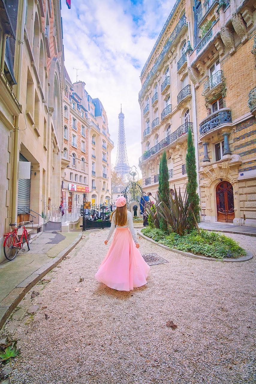 a girl in a pink skirt on a side street overlooking the Eiffel Tower on Ave Suffren one of hidden gems on this 1 day in Paris Itinerary