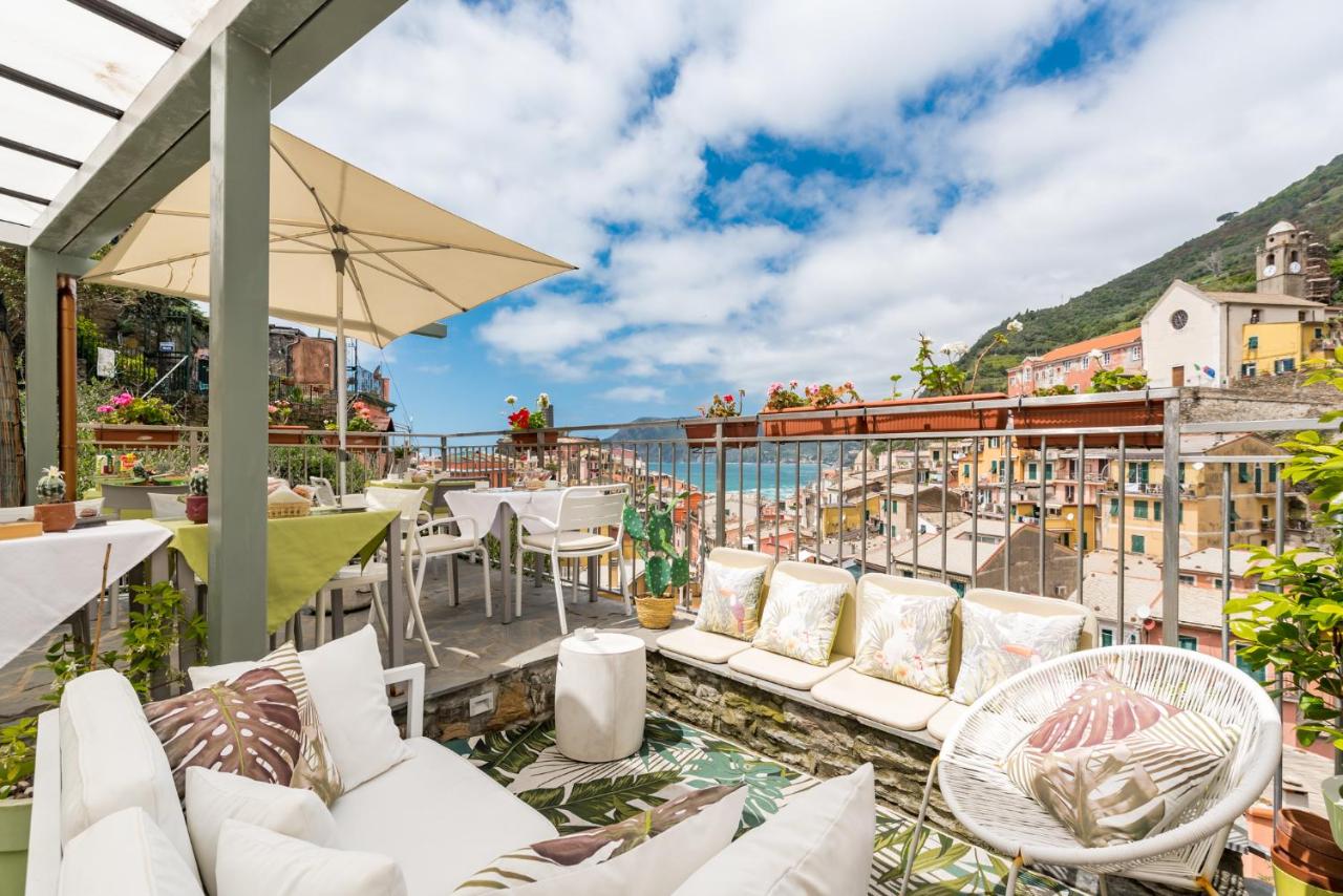 Lounge area on an open terrace with different chairs and tables and views of the sea and town.