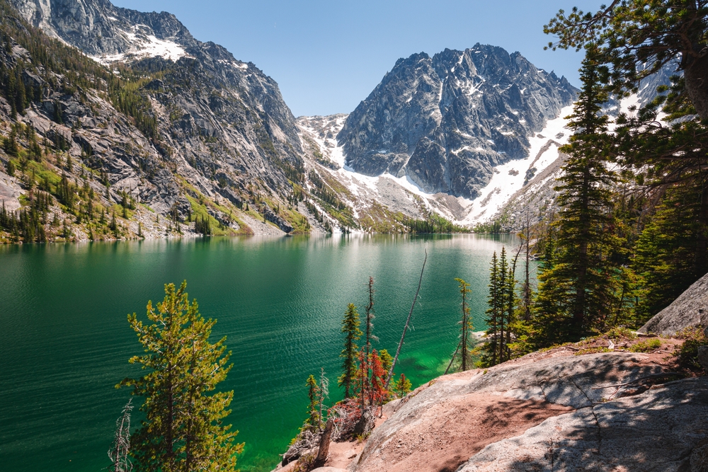 View down to green Colchuck Lake nestled at the bottom of mountains.