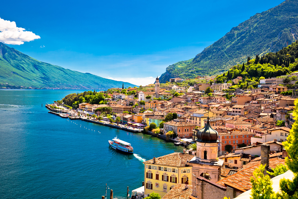 Aerial view of a quaint town on Lake Garda with a boat in the water.