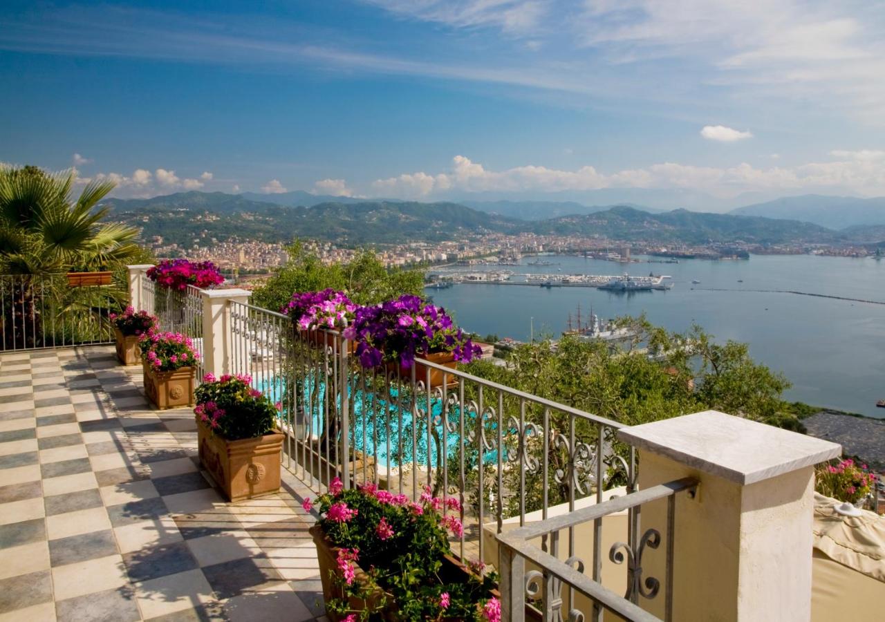 Tiled outdoor area overlooking a pool and the ocean with the city of La Spezia in the distance.