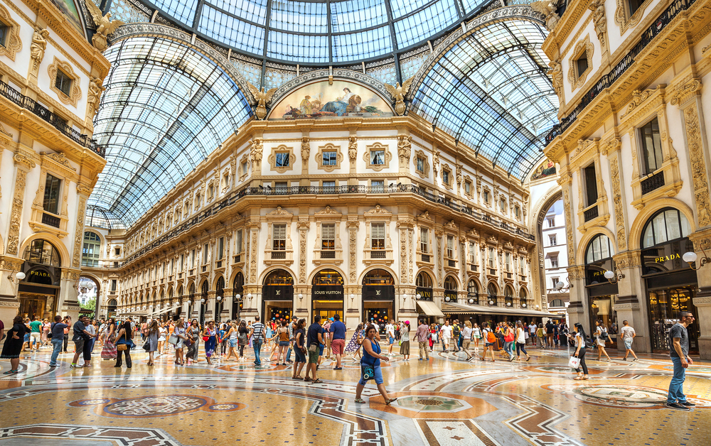 Inside the covered Galleria Vittorio Emanuele II with people shopping.