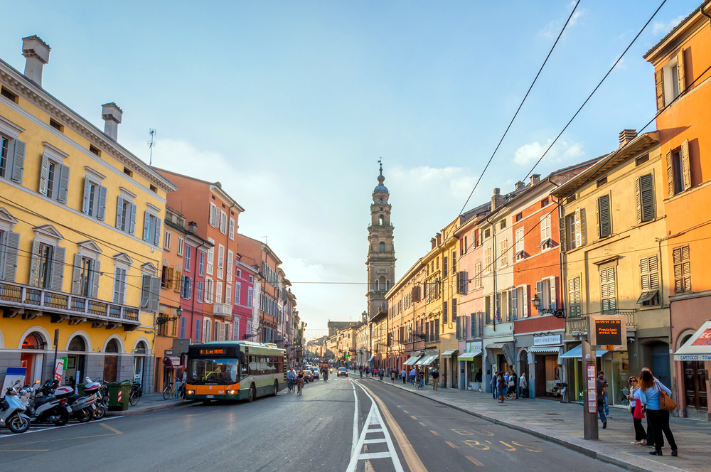 Street in Parma with a bus, people walking around, and colorful buildings.