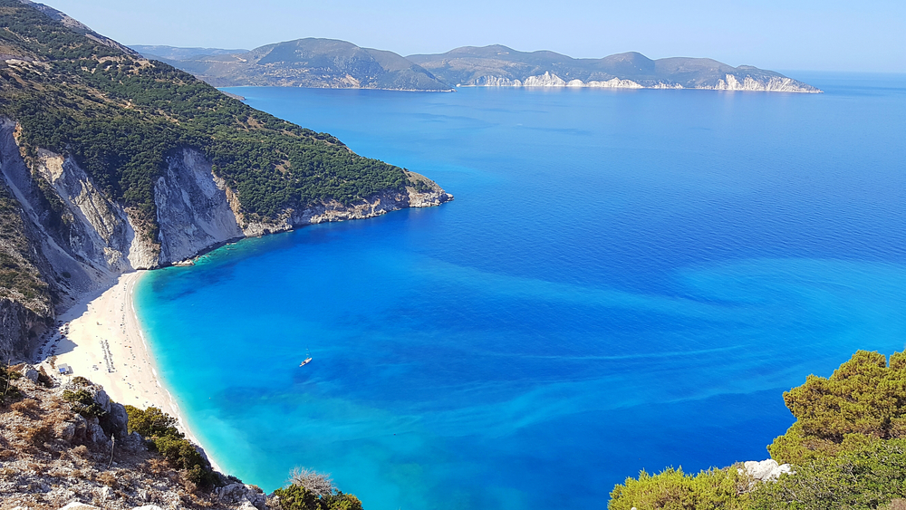 vast blue ocean visible in most of the photo, islands can be seen on the left and in the background, photo taken in Greece