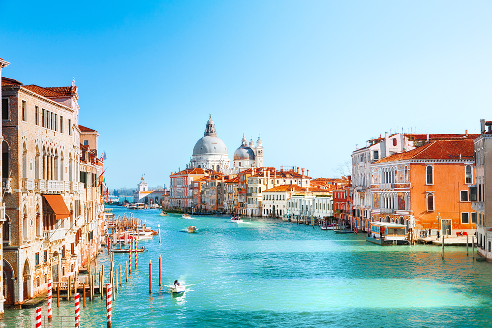 venice canal ways on a bright spring day, boats are in the water and building are on both sides 