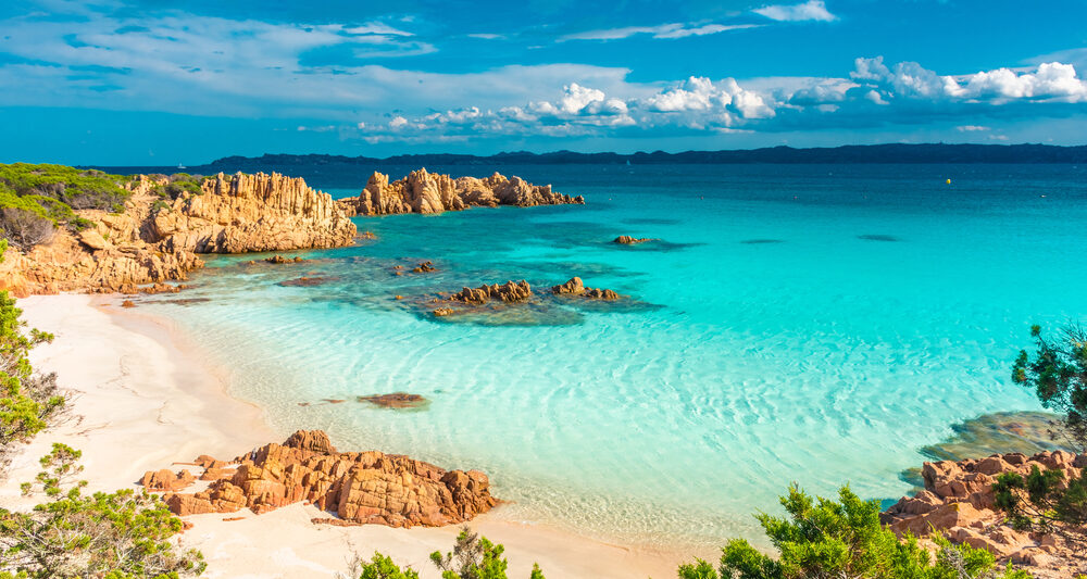 beautiful blue waters with blue sky and clouds and rocks at a beach in Sardinia