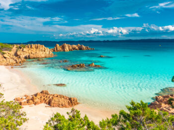 beautiful blue waters with blue sky and clouds and rocks at a beach in Sardinia