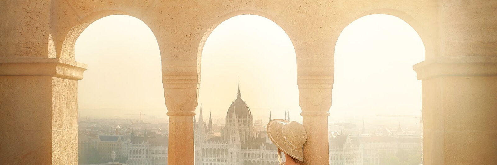 woman sitting in a pink skirt with buildings in Budapest, Hungary in the background at sunrise