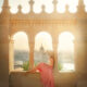 woman sitting in a pink skirt with buildings in Budapest, Hungary in the background at sunrise