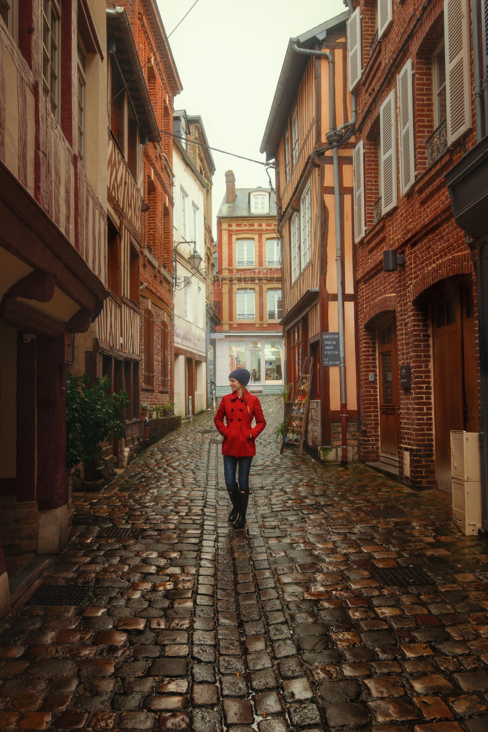 Girl in a red coat walkign throug a European street in winter. 