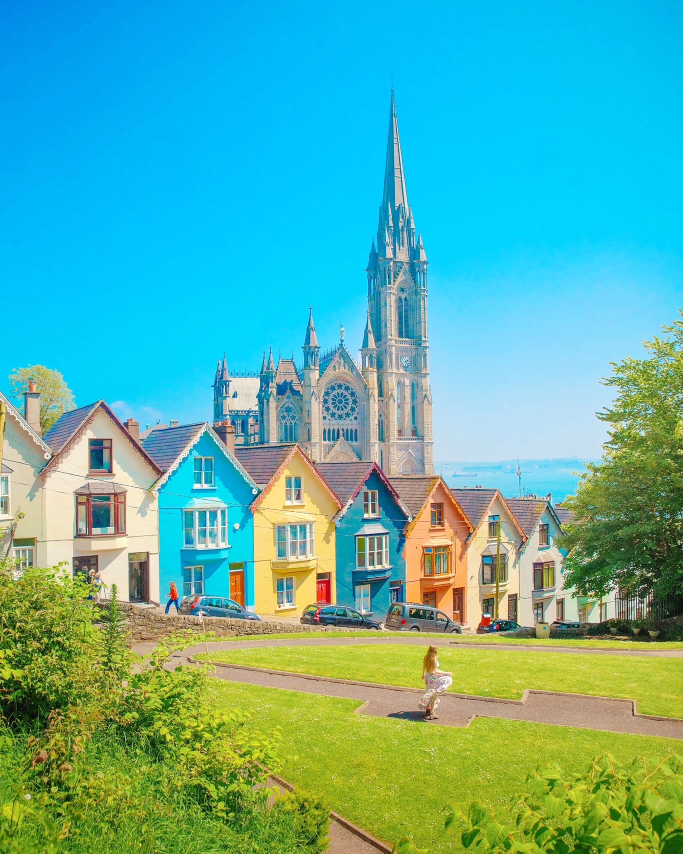 Girl in front of some colorful houuses in Ireland with a church in the background. The article is about the best time to visit Europe. 