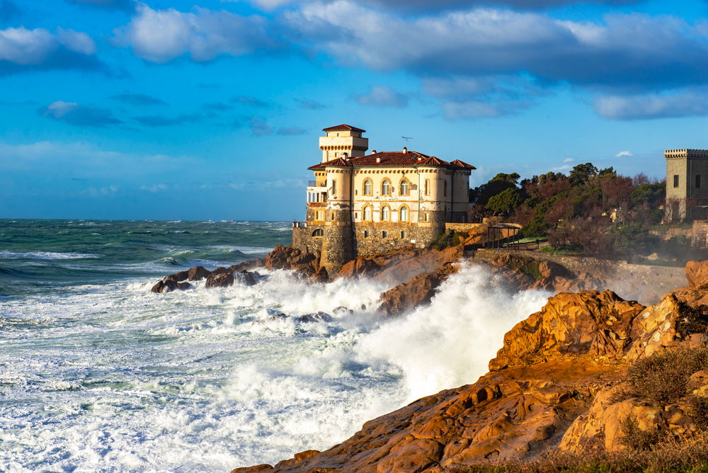 One of the many castles in Tuscany. This one is white and brick and is built on a rock the waves are crashing againist the rocks. 