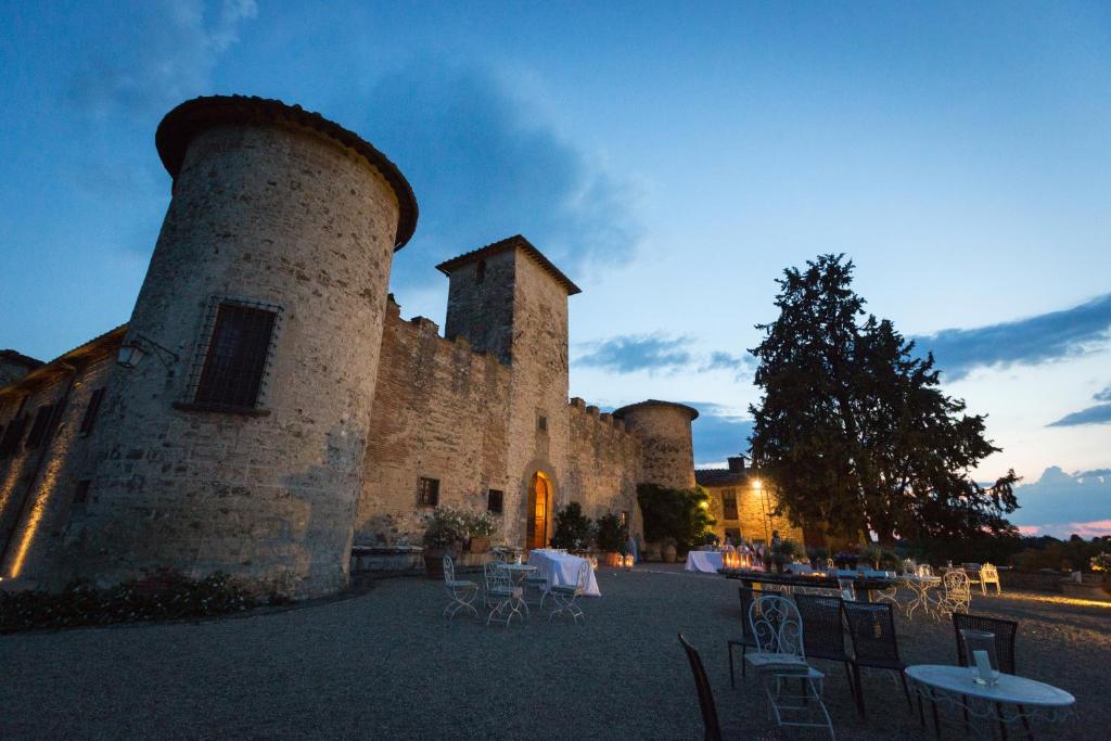 an imposing castel in the evening with tables and chairs set up outside. 