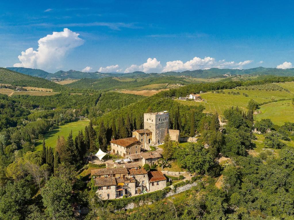 A sprawling castle complex on a hill surrounded by trees. There is a large tower in the background. 