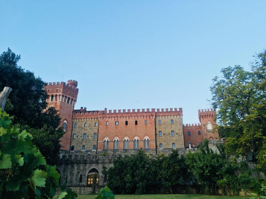 The side of a turrented castle with trees in front. 