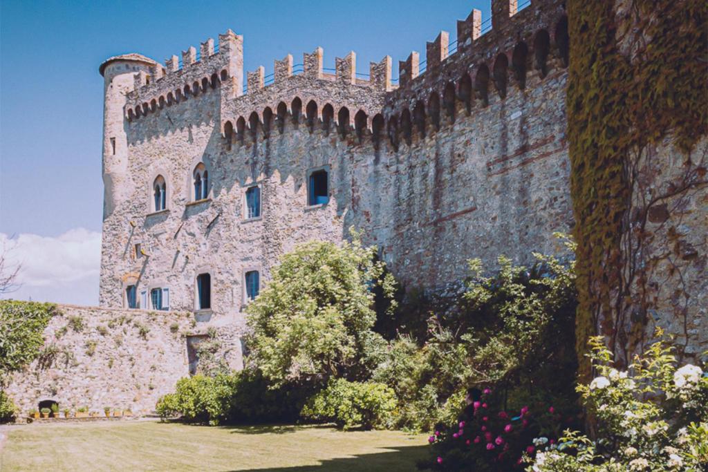 a castle close up with ivy on it plants and flowers in front. 